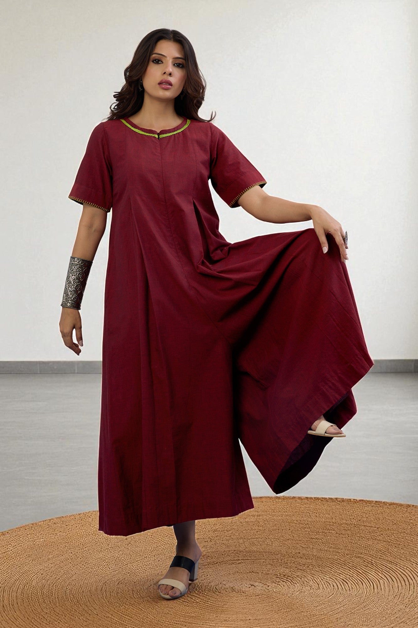 Woman wearing a maroon jumpsuit dress with a plain background